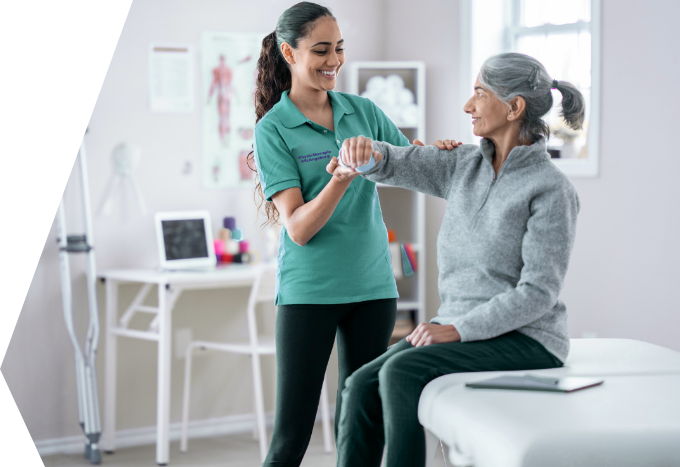 Physiotherapeutische Übung mit einer sitzenden Person in einem hellen Behandlungsraum einer Physiotherapiepraxis.